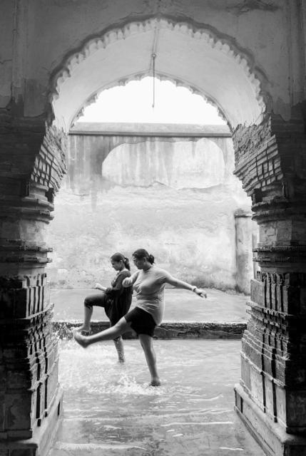 Two women kick water on the street.