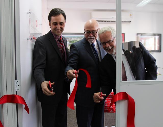 Three men cut ribbon in doorway