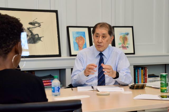 Male wearing a tie speaks at table in office setting