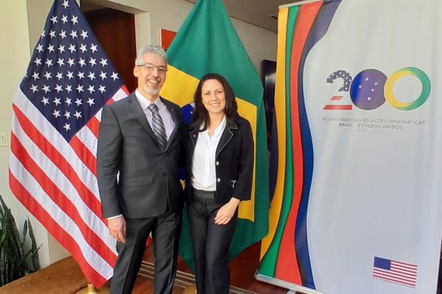 Male and female pose in front of Brazil and U.S. flags