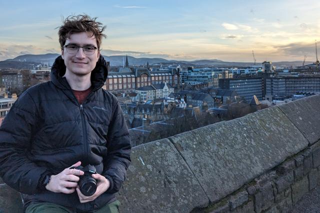 Young man poses in front of European skyline