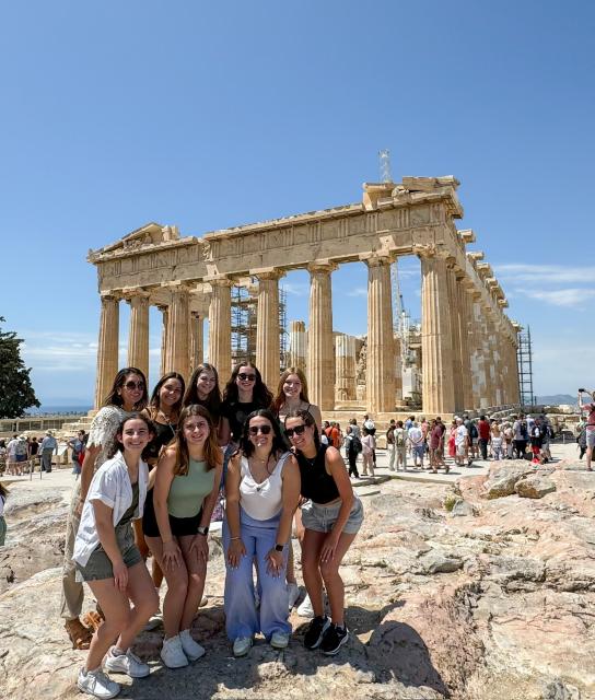 A group of young women pose in front of the Parthenon