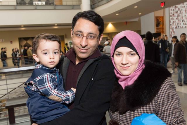 A family smiling at the camera during the Office of International Affairs' Thanksgiving Dinner event.