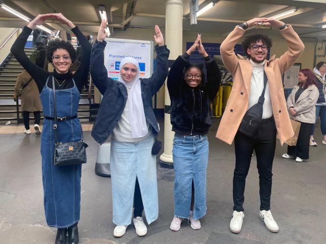 Four people spelling out O-H-I-O with their arms raised.