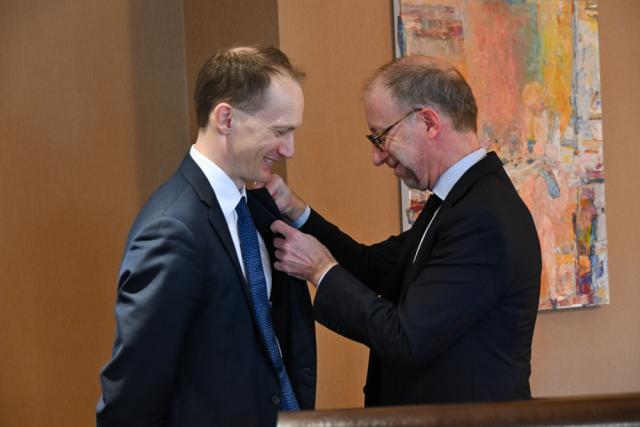 A man pins an award on another man's lapel.
