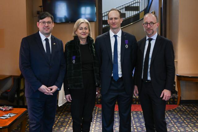 Four people in suits pose.