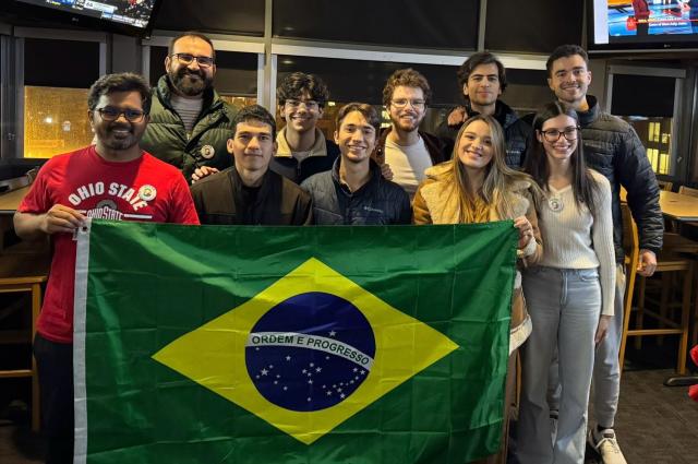 Ten people holding a Brazilian flag