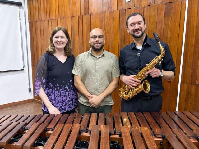 Three musicians - one holding a saxophone