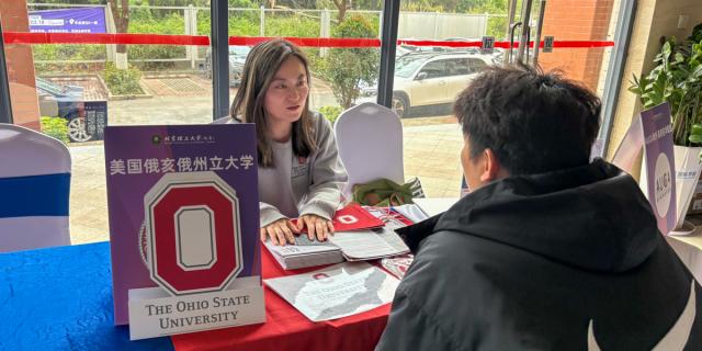 Woman speaks to student at a table