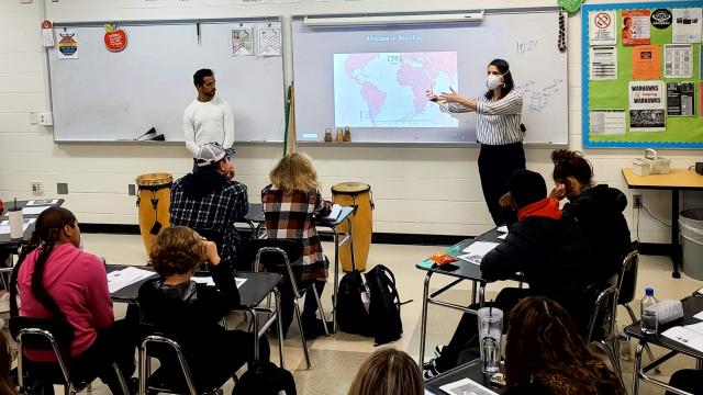 Women standing in front of board teaching a class about Brazil