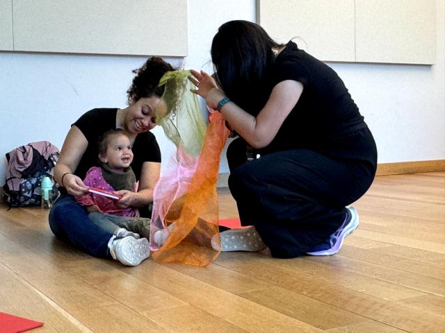 Teachers with smiling baby and scarves.