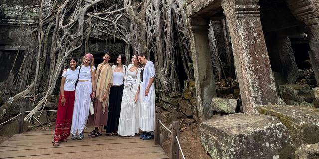 Students posing near tree roots and ancient ruins