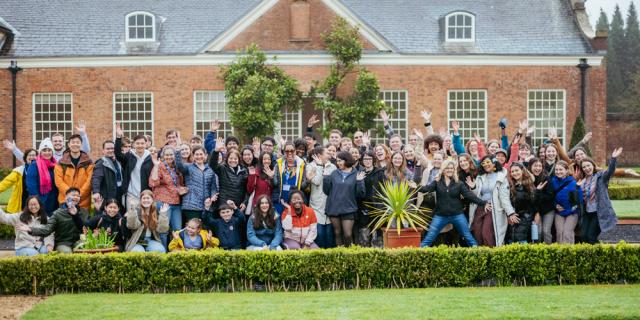 Large group posing outside waving arms