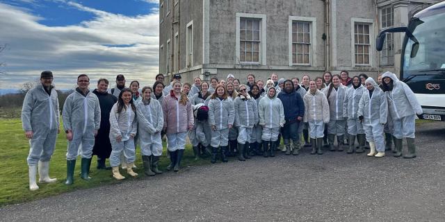 Students standing in lab gear in front of lab