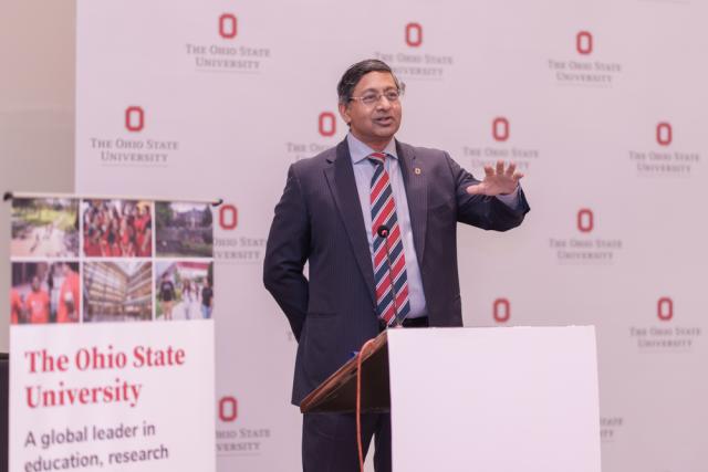 Male wearing business clothes speaks at podium