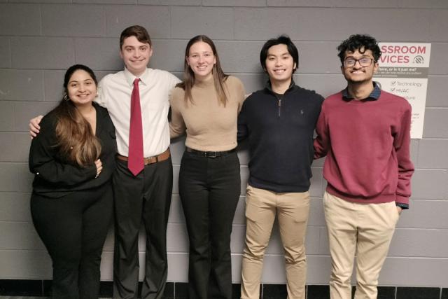 Five students pose after giving a presentation