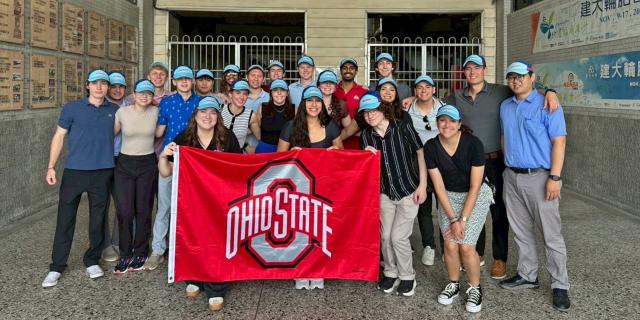 students with an ohio state flag in front of business