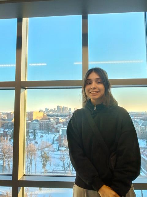 Woman standing by window with view of city in background