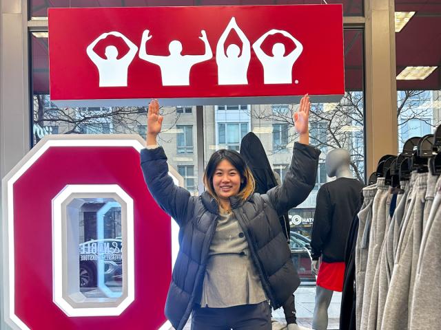 Woman holding her arms straight up in shape of an H.