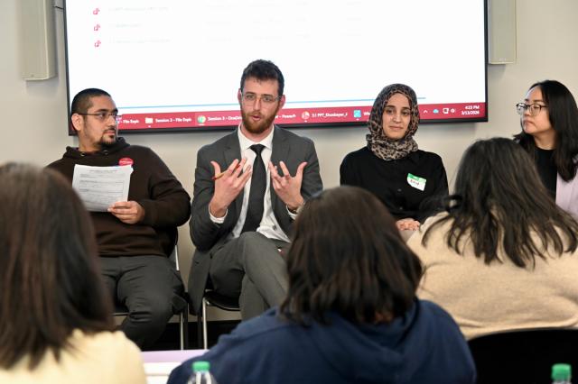 Man in suit presents on a panel discussion.