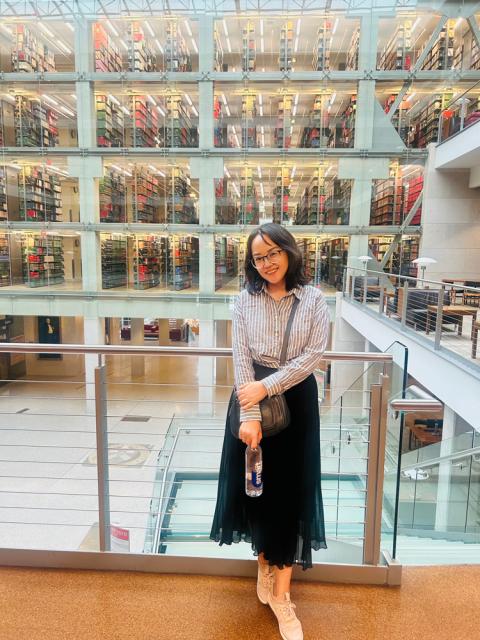 Woman standing with library stacks behind her.