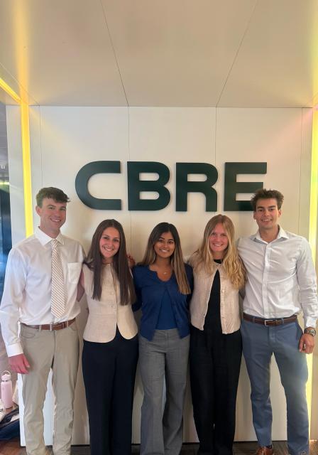 Students in business attire in front of CBRE sign