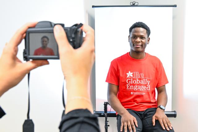 Male poses for photo in front of screen.