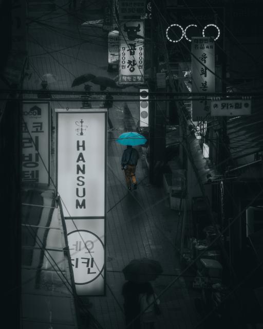 Person walking in the rain with a blue umbrella