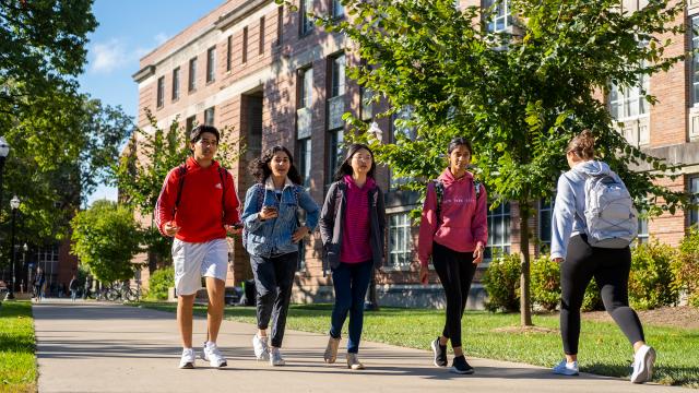 Group of Students walking across campus on a bright day