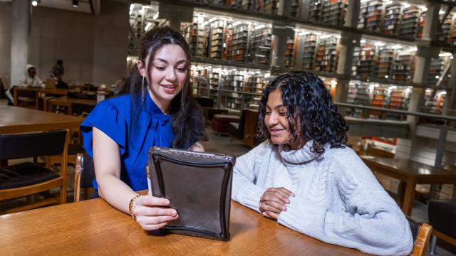 Young person showing a friend something on a tablet in Thompson Library