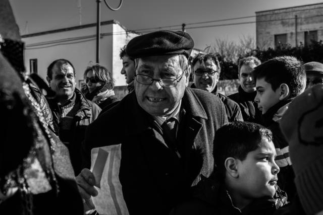 Older man among a group of men and boys.