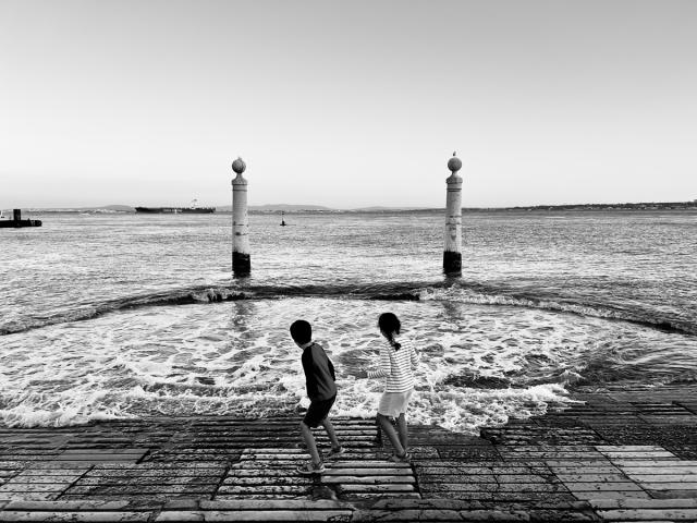 Two kids playing by the shore of Rio Tejo.