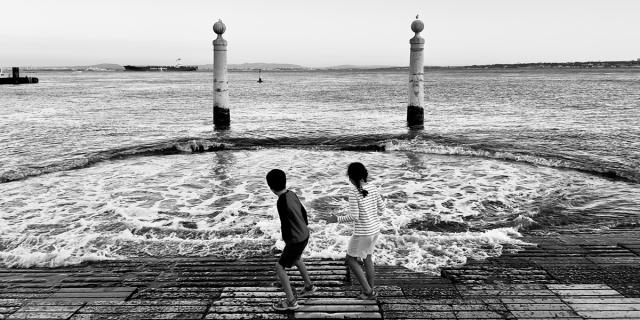 Two children playing by the edge of a lake.