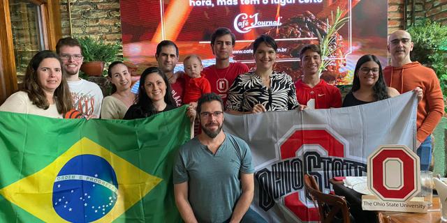 A group of people standing with the Brazil and Ohio State flags at the Brazil Send Off Event.