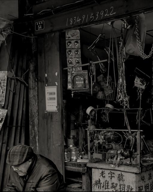 Old man sitting outside of a Chinese locksmith shop