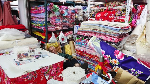 Man sleeping in room full of fabrics