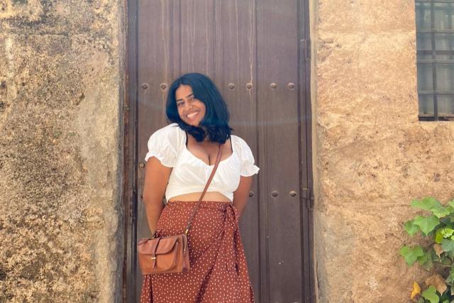 Young woman poses in front of Spanish door