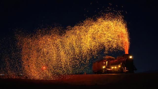 Steam engine train spraying sparks at night