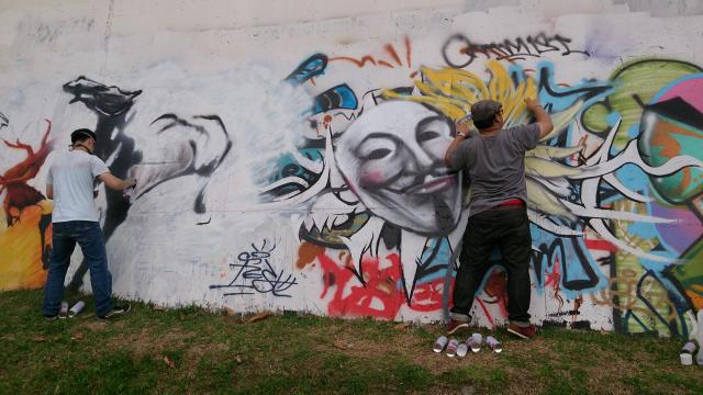 two men painting graffiti on wall