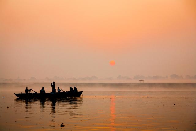 Silouhette of a boat with fishermen on it.