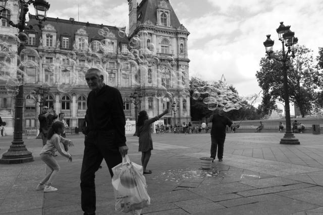 Kids with large bubbles in outdoor square in city.