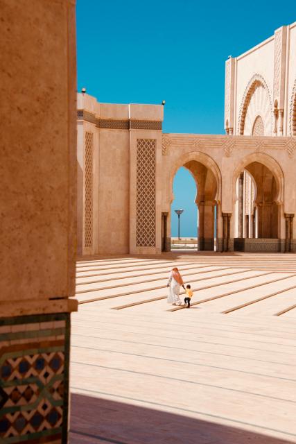 Mother holds son's hand as they walk through mosque.