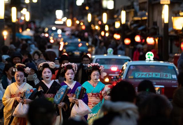 Four geisha women walk along a street