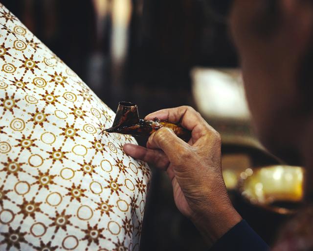 person drawing a pattern on fabric