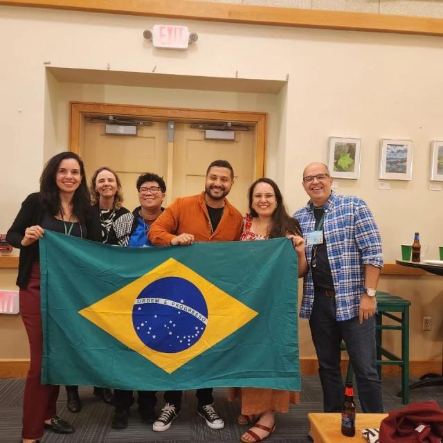 A group of people standing with the Brazil flag.