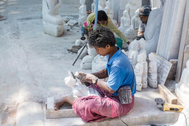 A marble artisan works alongside the road 