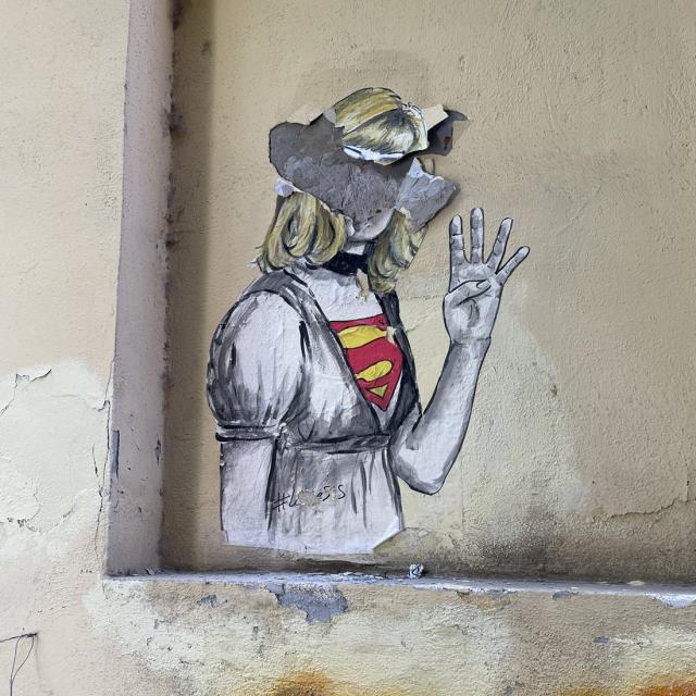 Mural of female holding up her hand with four fingers dressed with Superwoman shirt 