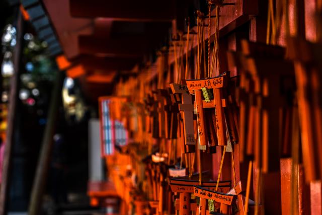 A series of small orange torii gates hang on strings, each inscribed with Japanese characters. 