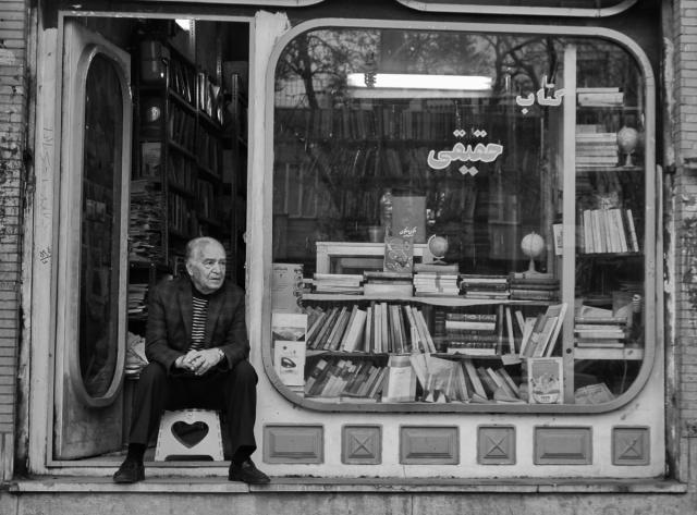 Man sitting in doorway of a book shop.