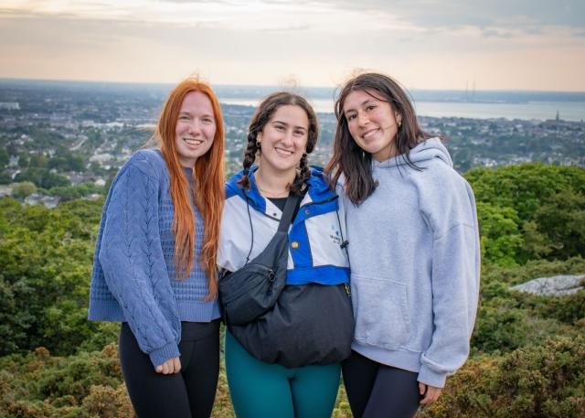 Three young women pose in front of an Irish landscape